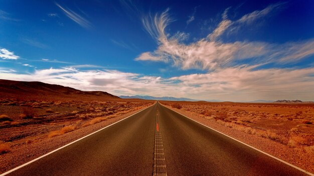 Camino de hormigón negro claro bajo cielos blancos y azules