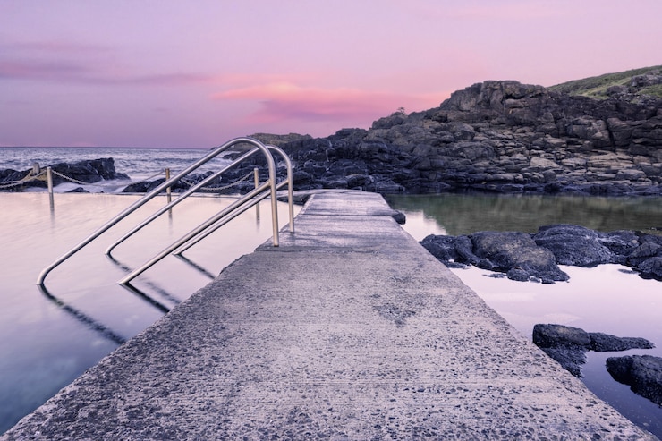 Foto gratuito camino de piedra en la formación de agua a la orilla del mar durante el atardecer