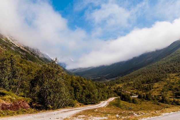 Camino de tierra sinuoso recto en el paisaje de montaña verde