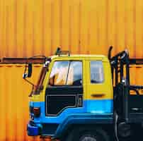 Foto gratuita camión amarillo estacionado cerca de una caja de contenedor amarillo