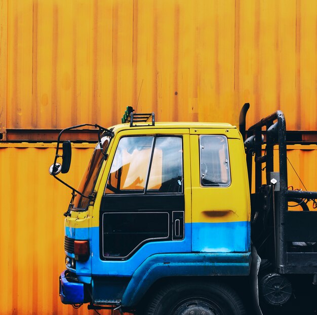 Camión amarillo estacionado cerca de una caja de contenedor amarillo