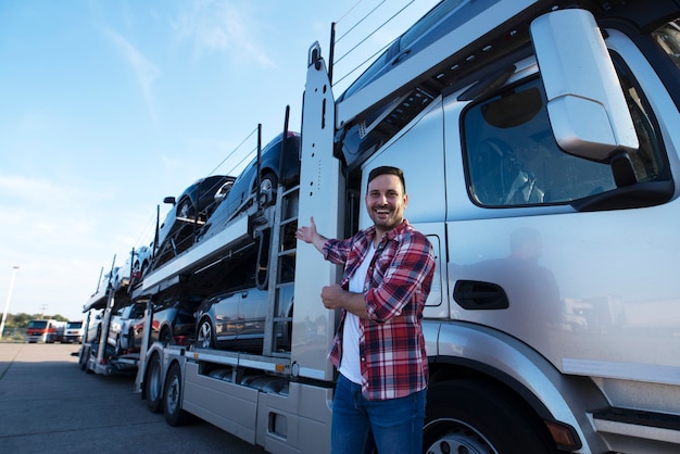 Camionero de mediana edad delante del remolque de camión con coches