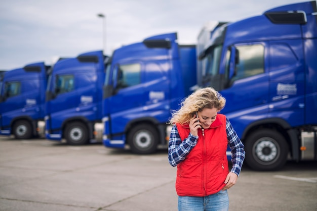 Camionero mujer hablando por teléfono sobre el envío que debe entregarse