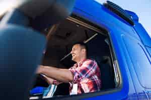 Foto gratuita camionero profesional de mediana edad en la cabina de conducción de camiones y sonriendo