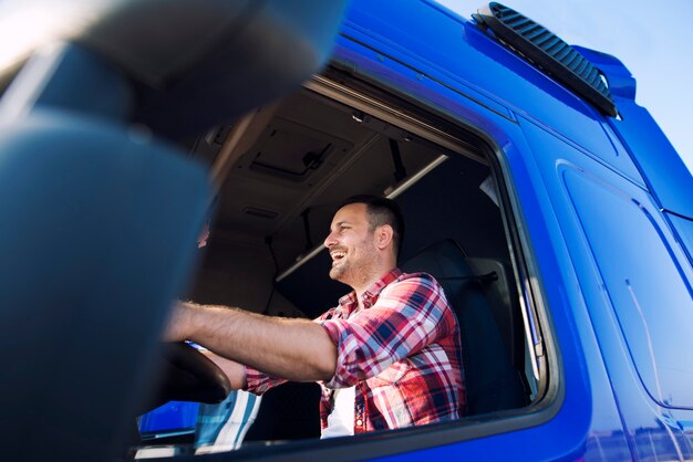 Camionero profesional de mediana edad en la cabina de conducción de camiones y sonriendo