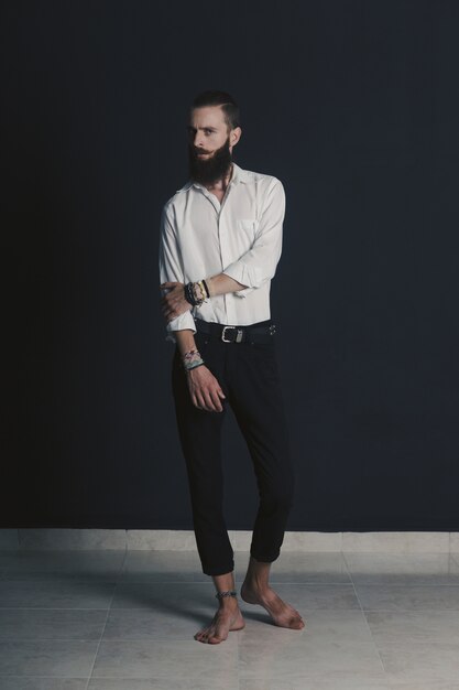 Camisa blanca de hombre con barba estilo hipster en estudio sobre fondo negro