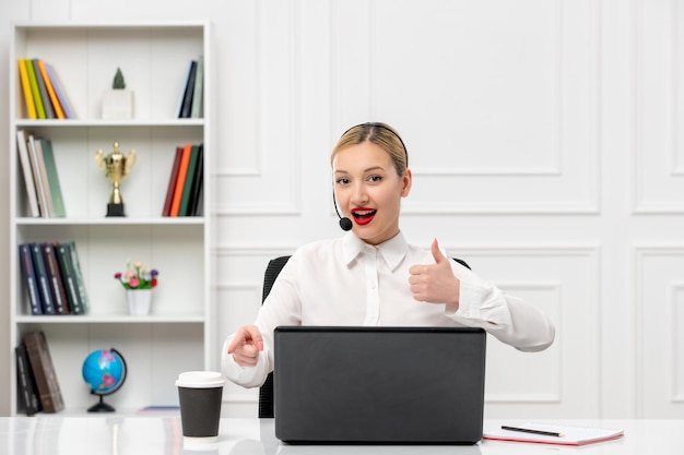 Camisa de oficina de linda chica rubia de servicio al cliente con auriculares y computadora que muestra un buen gesto