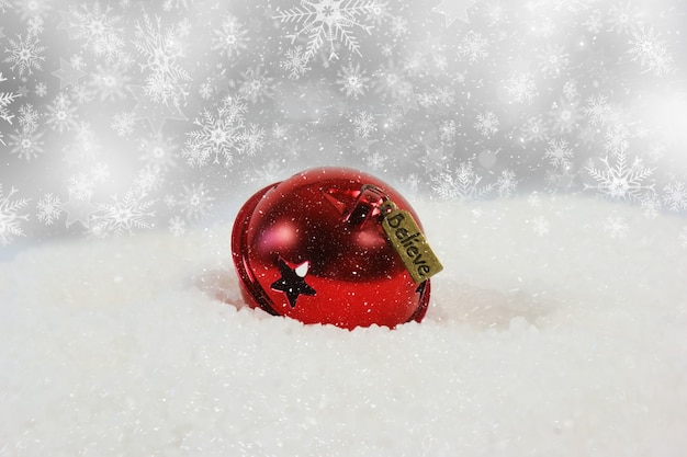Foto gratuita campana de navidad con etiqueta de creer ubicado en la nieve