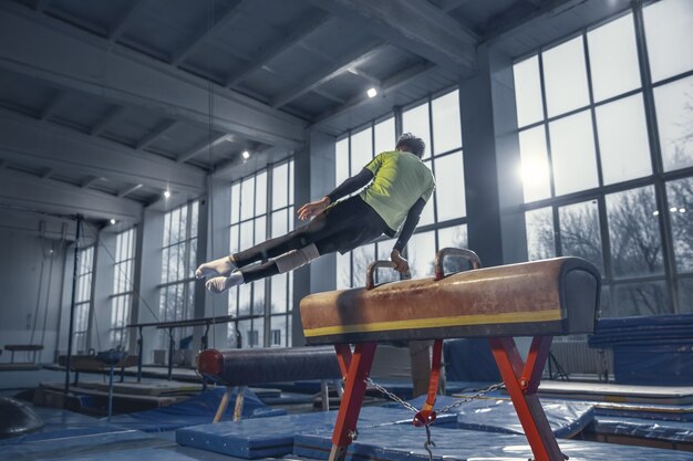 Campeón. Pequeño gimnasta masculino entrenando en gimnasio, flexible y activo