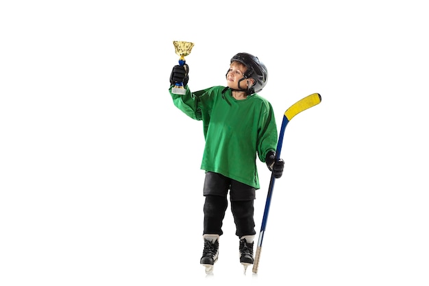 Campeón. Pequeño jugador de hockey con el palo en la cancha de hielo y pared blanca. Deportista con equipo y casco de entrenamiento. Concepto de deporte, estilo de vida saludable, movimiento, movimiento, acción.