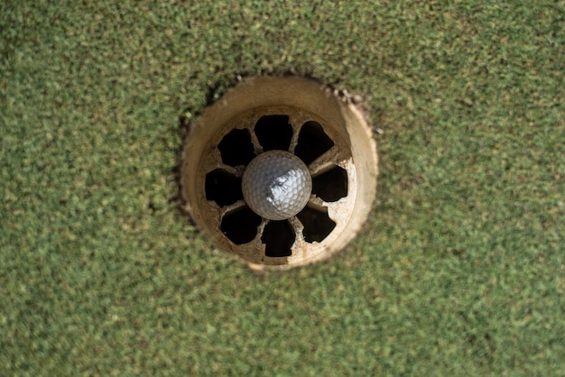 Campo de golf con bola blanca dentro del hoyo