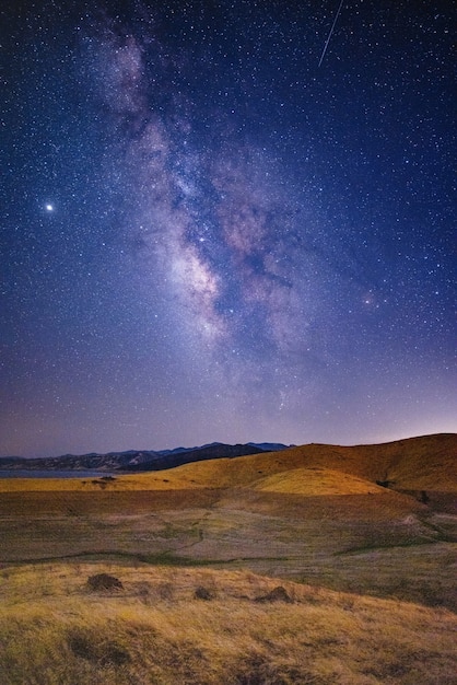 Foto gratuita campo de hierba verde y marrón bajo un cielo azul con estrellas durante la noche