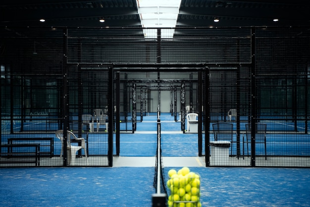 Campo de padel con pelotas en canasta