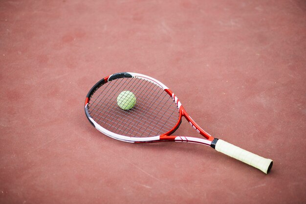 Campo de tennies de alto ángulo con pelota y raqueta