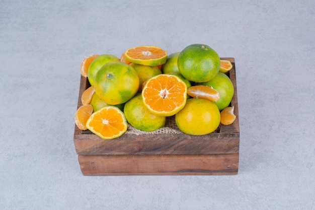 Una canasta de madera llena de mandarinas en rodajas sobre fondo blanco. Foto de alta calidad