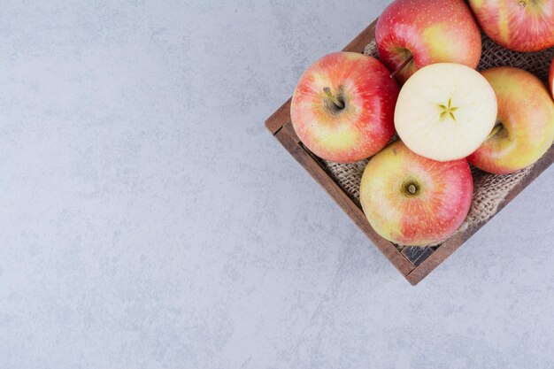 Una canasta de madera llena de manzanas sobre fondo blanco. Foto de alta calidad