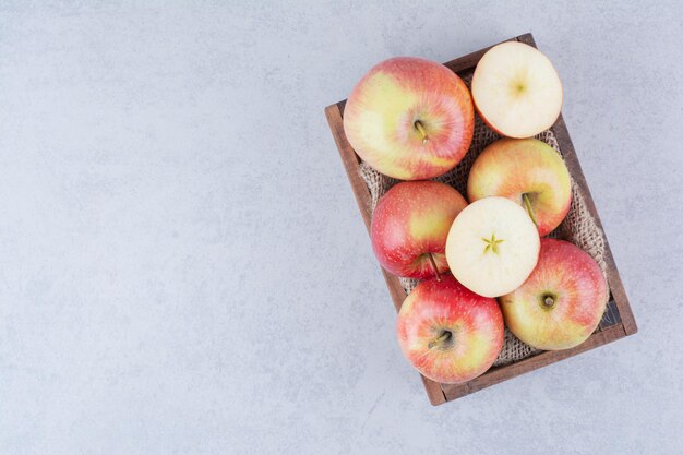 Una canasta de madera llena de manzanas sobre fondo blanco. Foto de alta calidad