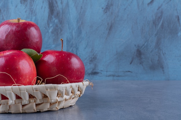 Foto gratuita una canasta de manzanas y hojas sobre la superficie oscura.