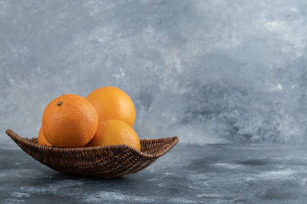 Una canasta de mimbre llena de frutas naranjas.