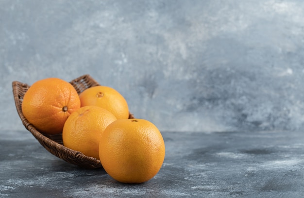 Una canasta de mimbre llena de frutas naranjas.