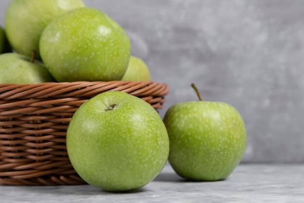 Una canasta de mimbre de manzanas verdes frescas en piedra