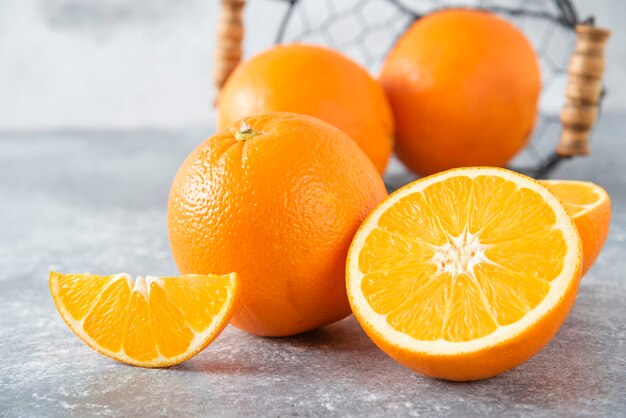 Una canasta negra metálica llena de jugosas frutas de naranja en la mesa de piedra.