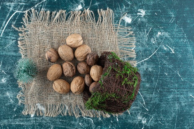 Una canasta con nueces saludables y arbolito de Navidad sobre una tela de saco. Foto de alta calidad