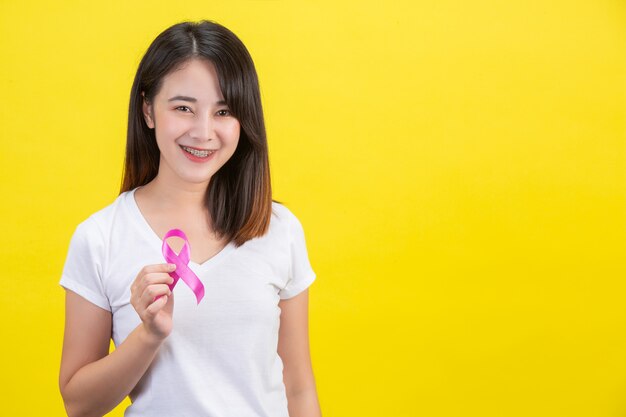 Cáncer de mama, una mujer con una camiseta blanca con una cinta de raso rosa en el pecho, un símbolo para la concientización del cáncer