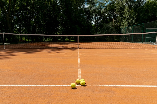 Cancha de tenis con pelotas de tenis en el suelo