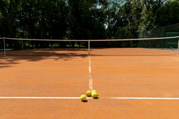 Cancha de tenis con pelotas de tenis en el suelo