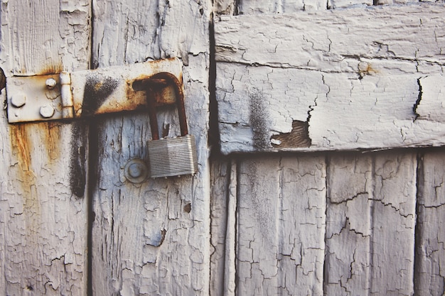 Foto gratuita candado oxidado colgando de una antigua puerta de madera blanca