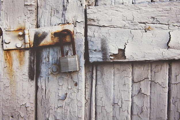 Candado oxidado colgando de una antigua puerta de madera blanca