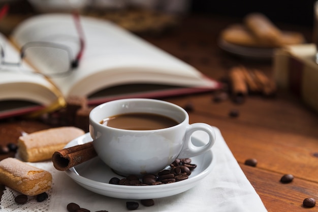 Canela y galletas cerca de la taza de café