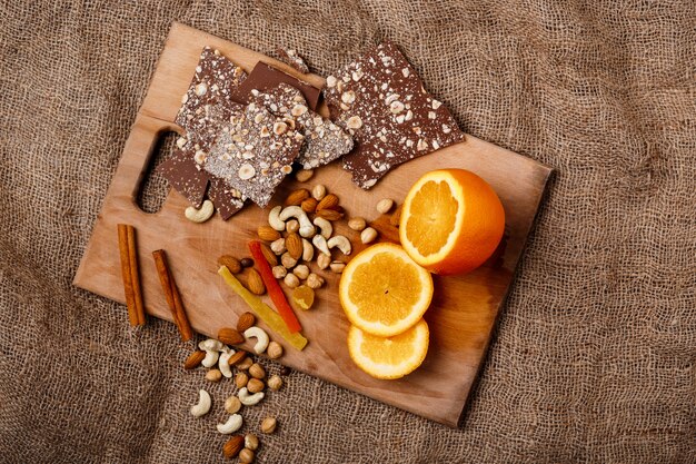 Canela y nueces anaranjadas del chocolate en el escritorio de madera.