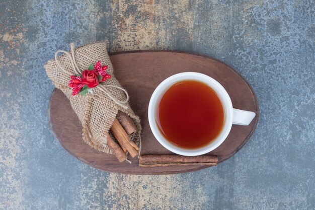 Canelas en arpillera y taza de té en placa de madera. Foto de alta calidad