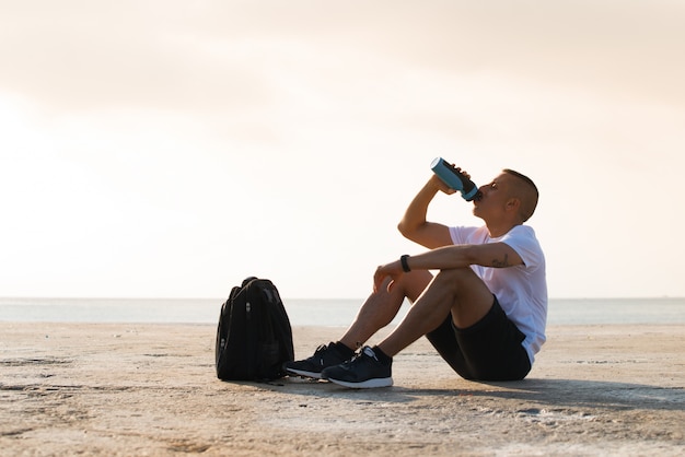 Cansado, joven, deportista, beber, agua, suelo