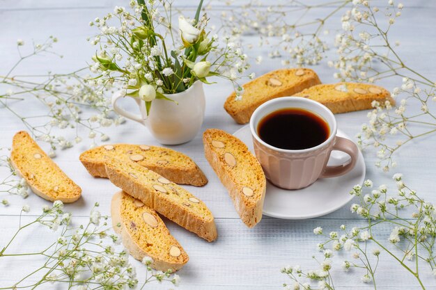 Cantuccini, galletas tradicionales toscanas italianas con almendras, una taza de café a la luz