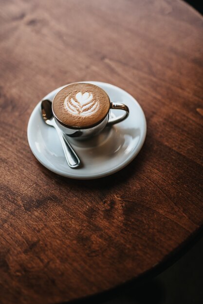 Cappuccino bellamente hecho servido con arte floral en el tiro de espuma desde la vista aérea