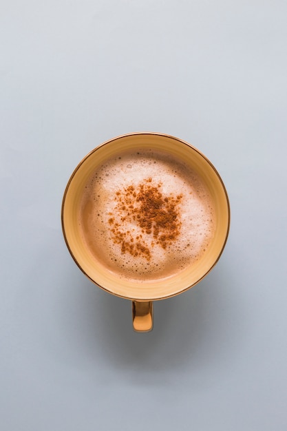 Cappuccino en una taza con chocolate en polvo sobre fondo blanco