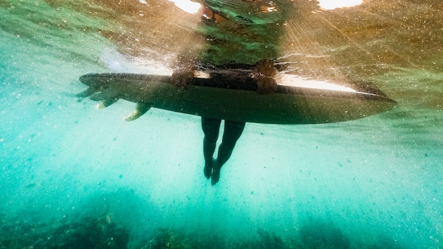 Captura bajo el agua de mujer con tabla de surf