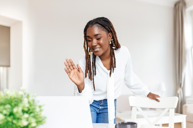 Foto gratuita captura de una mujer de negocios en una videollamada mientras está sentada en su escritoriocaptura recortada de una mujer joven atractiva que usa su computadora portátil para hacer una videollamada en casa