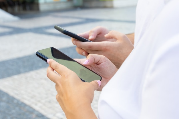 Captura recortada de jóvenes que usan teléfonos inteligentes en la calle