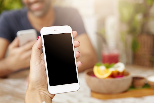 Captura recortada de la mano de la mujer caucásica con teléfono móvil genérico