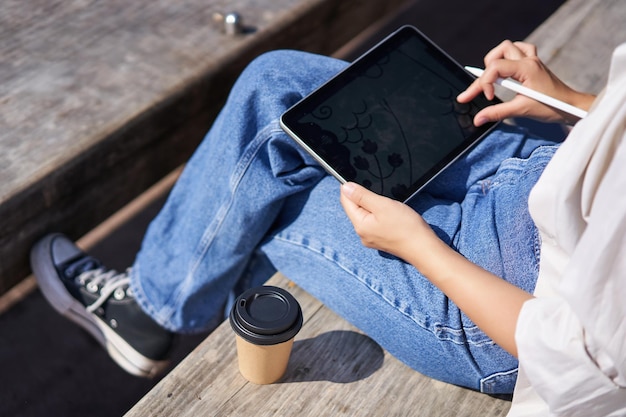 Captura recortada de manos femeninas dibujando en tableta gráfica digital con bolígrafo sentado con una taza de café o