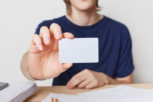 Captura recortada de manos masculinas jóvenes sostiene una tarjeta en blanco con espacio de copia para su texto o contenido publicitario