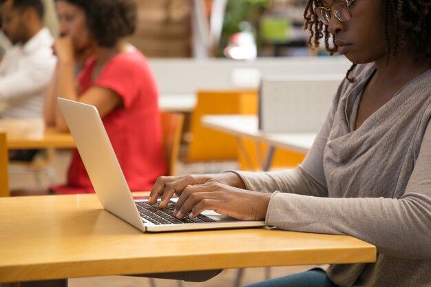 Captura recortada de mujer pensativa que trabaja con la computadora portátil en la biblioteca