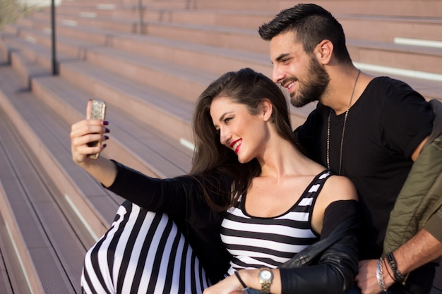 Capturando momentos brillantes. Pares amorosos jovenes alegres que hacen el selfie en la cámara mientras que se coloca al aire libre.