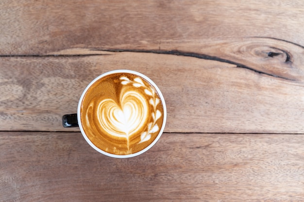 Capuchino caliente del café del arte en una taza en fondo de madera de la tabla con el espacio de la copia