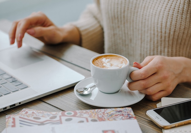 capuchino caliente con laptop sobre la mesa