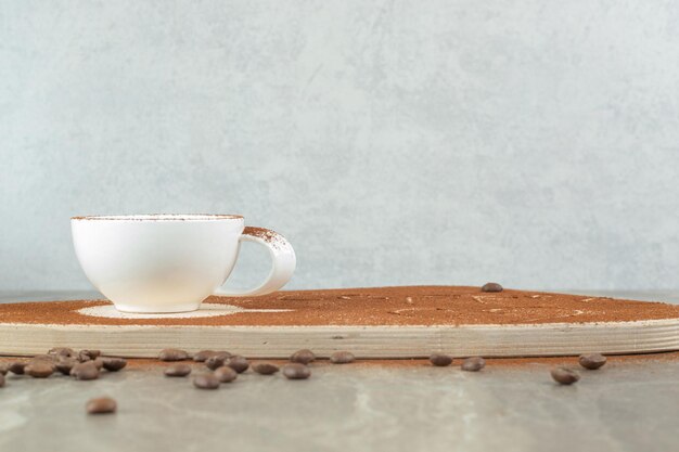 Capuchino sobre tabla de madera con granos de café.